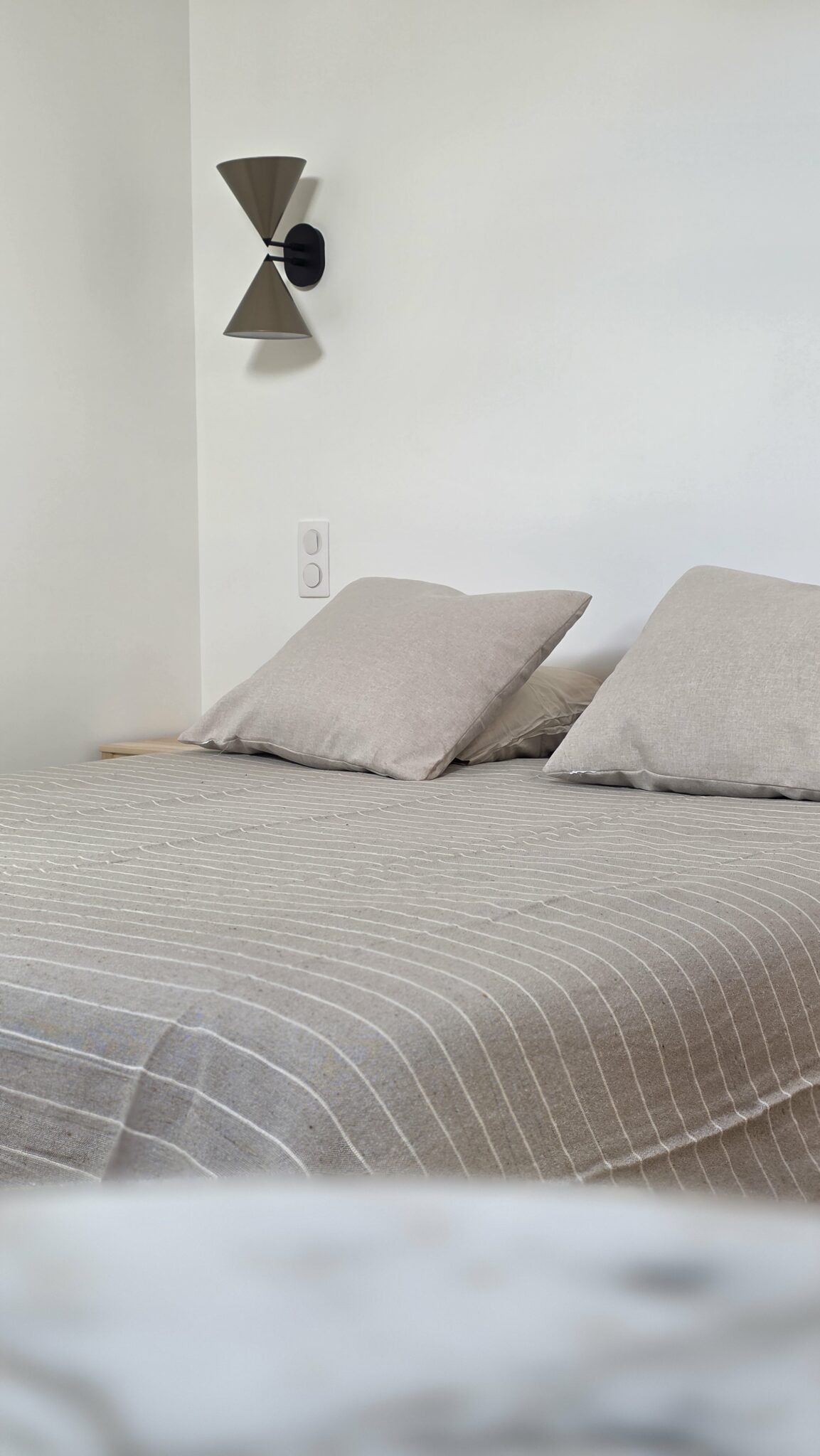 Lit double avec linge de lit et coussins dans la chambre du Perchoir à Metz